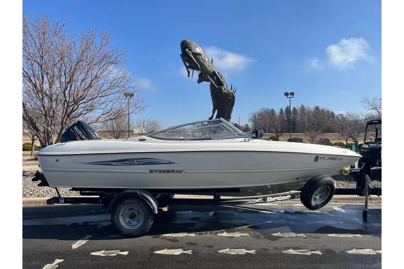 Slide: The Image of 2013 Stingray 191 RX boat on trailer, parked near large outdoor sculpture. - 2