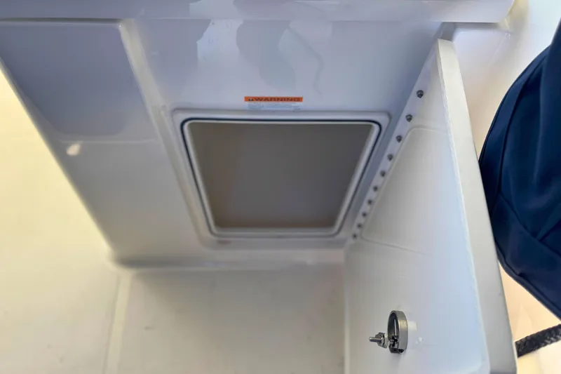 Slide: The Image of 2023 Pursuit DC 266 Dual Console storage compartment with open door and latch. - 11