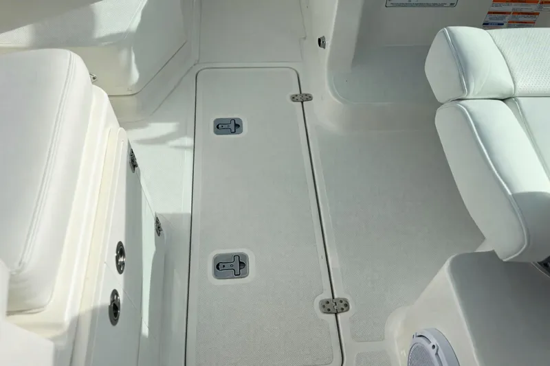 Slide: The Image of 2023 Pursuit DC 266 Dual Console boat interior with white seating and storage compartments. - 14