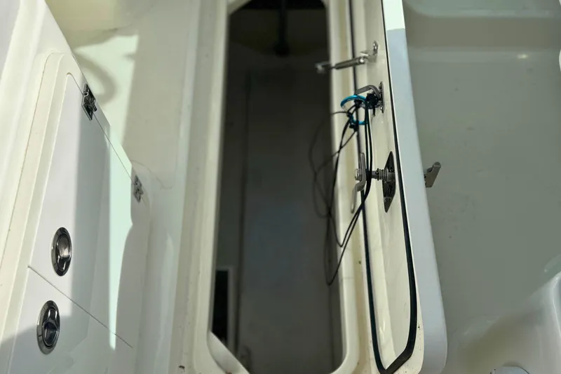Slide: The Image of 2023 Pursuit DC 266 Dual Console boat storage compartment with open hatch and visible wiring. - 15