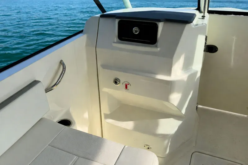 Slide: The Image of 2023 Pursuit DC 266 Dual Console interior with seating and storage, on calm water. - 17