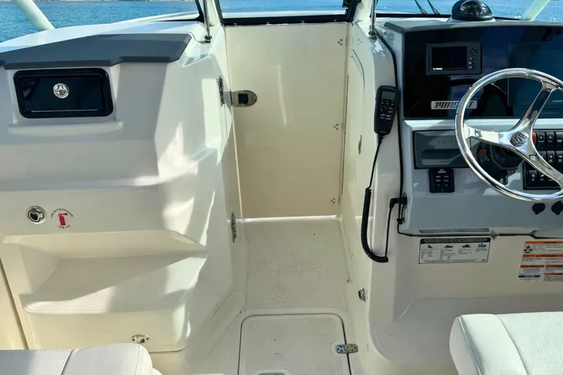 Slide: The Image of 2023 Pursuit DC 266 Dual Console boat interior with steering wheel and control panel. - 22