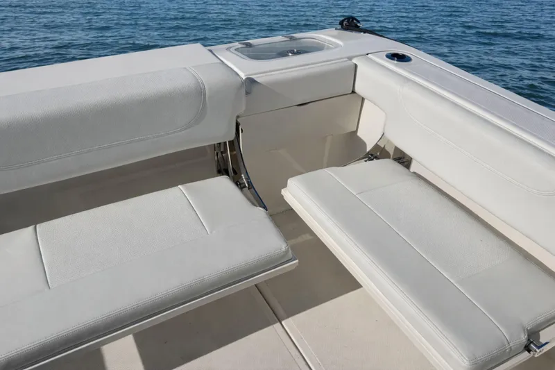 Slide: The Image of 2023 Pursuit DC 266 Dual Console boat interior with white seating and ocean backdrop. - 6