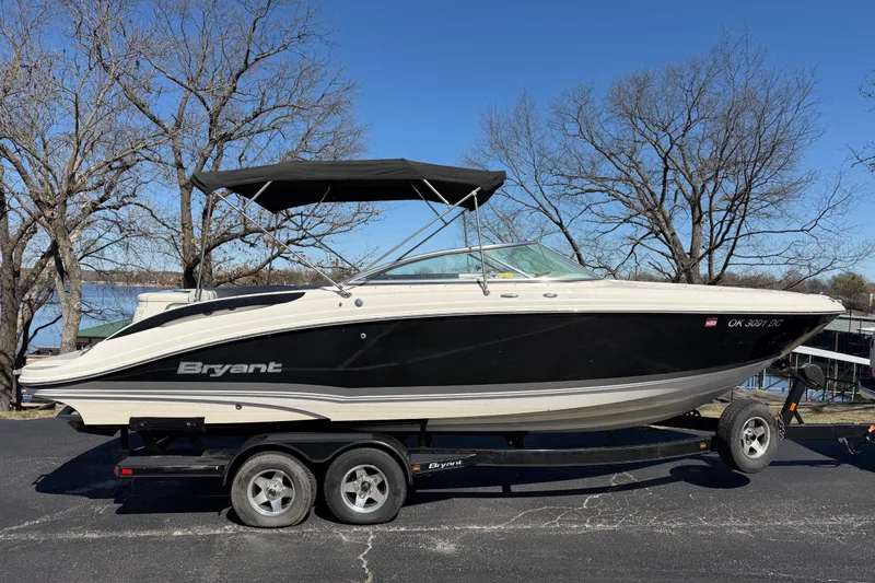 The Image of 2008 Bryant 268 boat on trailer, black and white design, parked near a lake. - 1