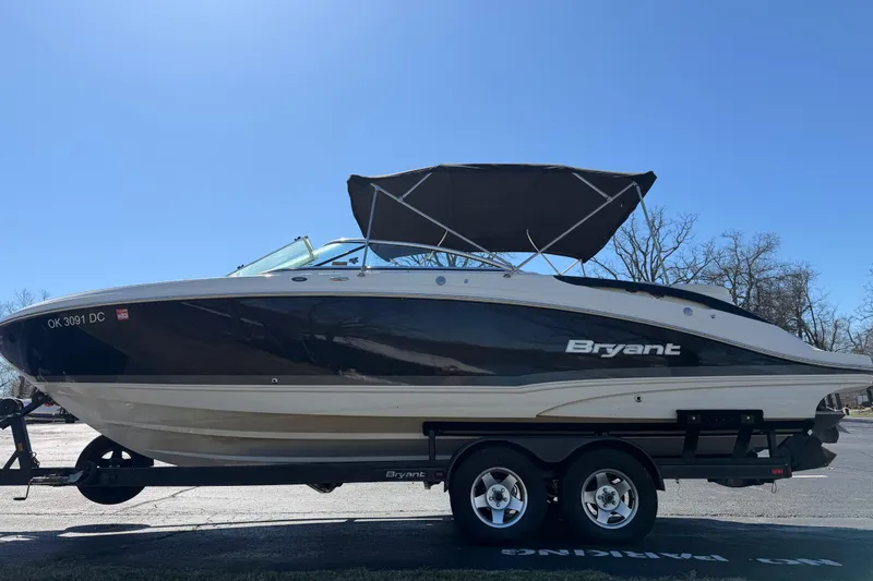 Slide: The Image of 2008 Bryant 268 boat on trailer with canopy, parked outdoors under clear sky. - 6