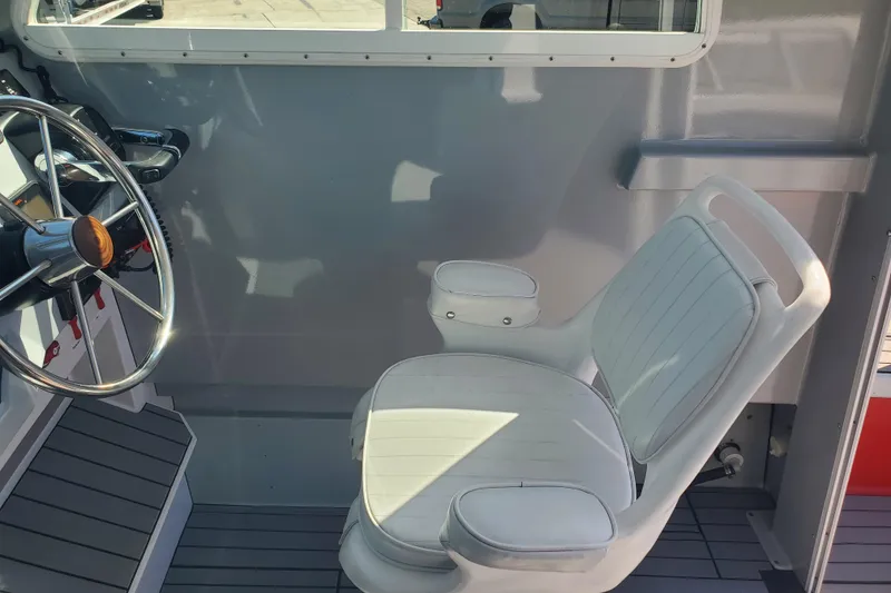 Slide: The Image of 1989 Boston Whaler Challenger interior with steering wheel and white captain's chair. - 12