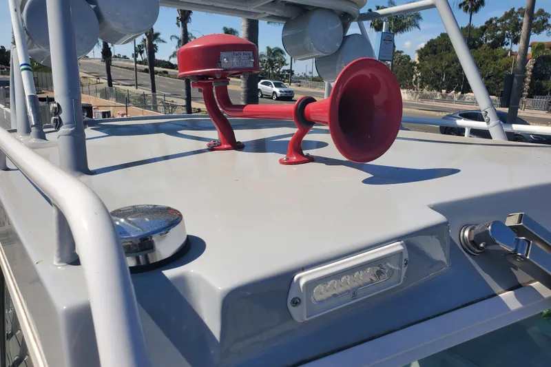 Slide: The Image of 1989 Boston Whaler Challenger boat with red horn on deck, parked near palm trees. - 30