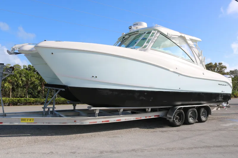 The Image of 2019 World Cat 320 DC boat on trailer, parked outdoors under clear blue sky. - 0