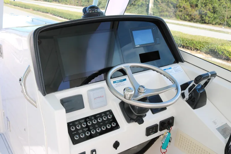 Slide: The Image of 2019 World Cat 320 DC helm with steering wheel, control panel, and navigation screens. - 10