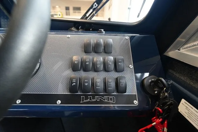 Slide: The Image of The image shows the dashboard of a Lund 185 Heavy Gauge Sport boat with multiple switches. - 30