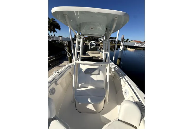 Slide: The Image of 2023 Key West 219 FS boat interior with seating and T-top, docked by calm water. - 3