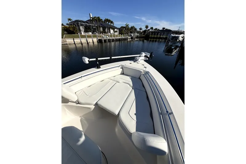 Slide: The Image of 2023 Key West 219 FS boat with cushioned seating, docked by a serene waterfront. - 7