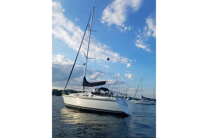 The Image of 1985 Hunter 31 sailboat on calm water under a blue sky with clouds. - 0