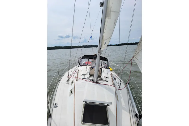 Slide: The Image of 1985 Hunter 31 sailboat navigating calm waters under a cloudy sky. - 6