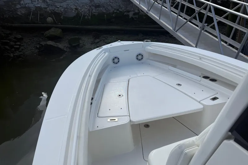 Slide: The Image of 2022 Regulator 23 boat interior with seating and storage, docked by a metal ramp. - 18