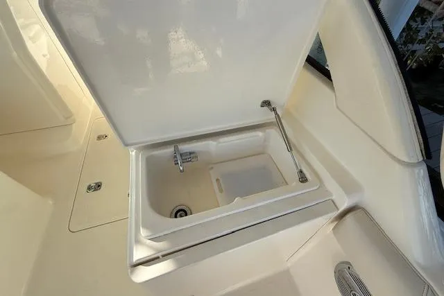 Slide: The Image of 2011 Pursuit DC 265 Dual Console boat sink with open lid and faucet. - 13