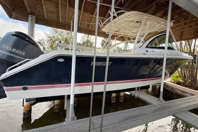Slide: The Image of 2011 Pursuit DC 265 Dual Console boat docked near waterfront buildings. - 2