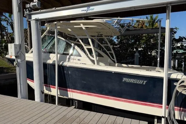 Slide: The Image of 2011 Pursuit DC 265 Dual Console boat docked under a lift, side view. - 5
