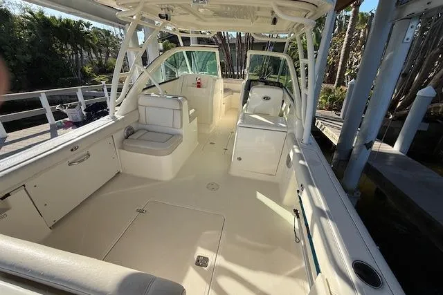 Slide: The Image of 2011 Pursuit DC 265 Dual Console boat interior with seating and helm, docked outdoors. - 9