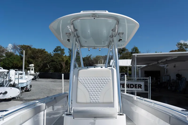 Slide: The Image of 2023 Contender 24 Sport boat with T-top and cushioned seating, parked outdoors. - 13