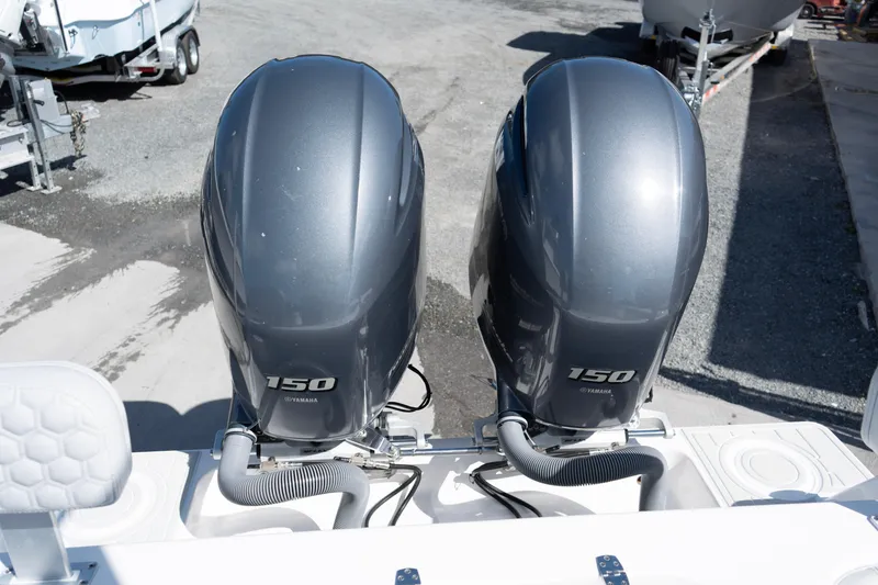 Slide: The Image of Twin Yamaha 150 engines on a 2023 Contender 24 Sport boat, parked on gravel. - 16
