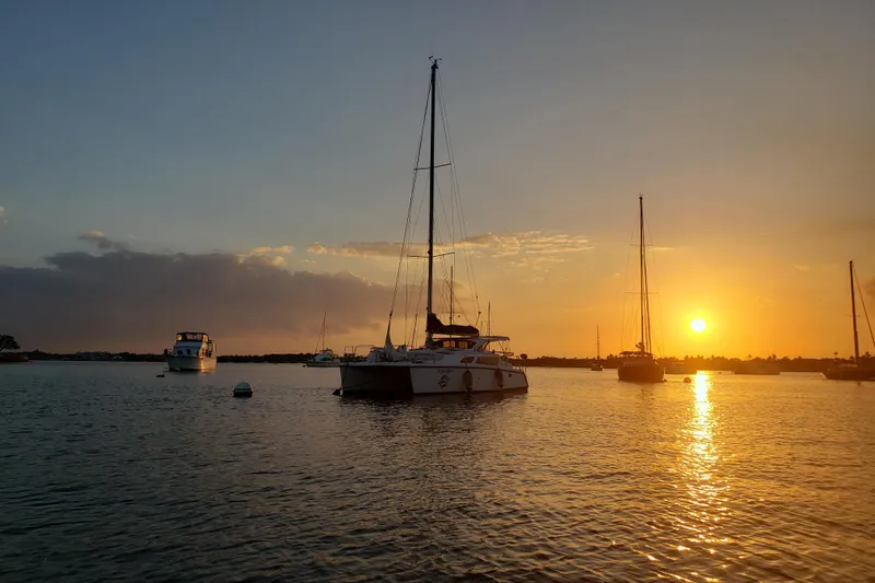 Slide: The Image of Sailboats at sunset on calm water, featuring a 2006 Gemini 105 MC. - 12