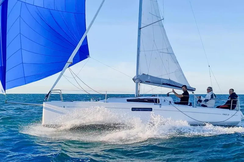 Slide: The Image of 2024 Beneteau First 27 sailboat with blue spinnaker sailing on open water. - 16