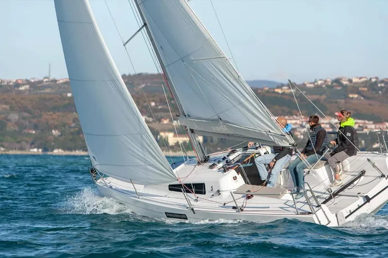 Slide: The Image of 2024 Beneteau First 27 sailboat with crew navigating coastal waters. - 17
