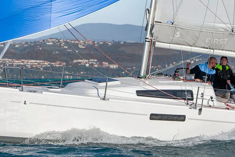 Slide: The Image of 2024 Beneteau First 27 sailboat navigating coastal waters with crew onboard. - 20