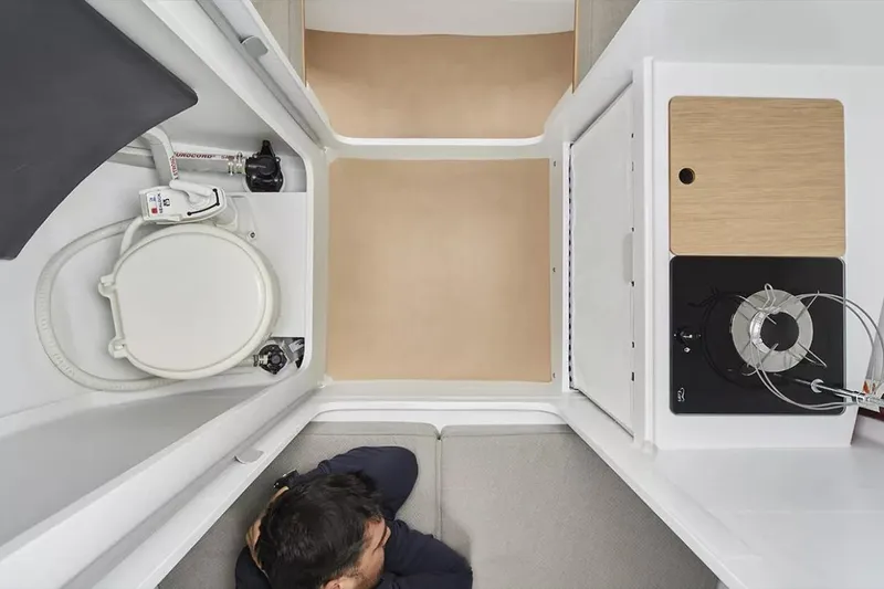 Slide: The Image of Interior of 2024 Beneteau First 27 sailboat, featuring compact kitchen and toilet area. - 21