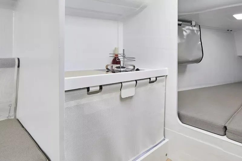 Slide: The Image of 2024 Beneteau First 27 interior with compact kitchen and cozy sleeping area. - 22