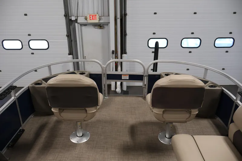 Slide: The Image of 2023 Sun Tracker Fishin' Barge 20 DLX interior with beige seating in a garage. - 11
