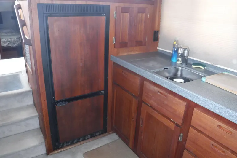 Slide: The Image of Interior of a 2002 Nordic Tug 37, featuring a wooden kitchen with sink and refrigerator. - 19