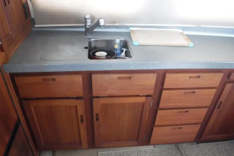 Slide: The Image of Wooden kitchen cabinets and sink in a 2002 Nordic Tug 37 boat interior. - 20