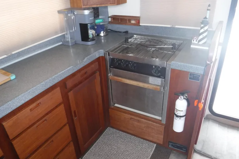 Slide: The Image of 2002 Nordic Tug 37 galley with stove, wooden cabinetry, and countertop appliances. - 21
