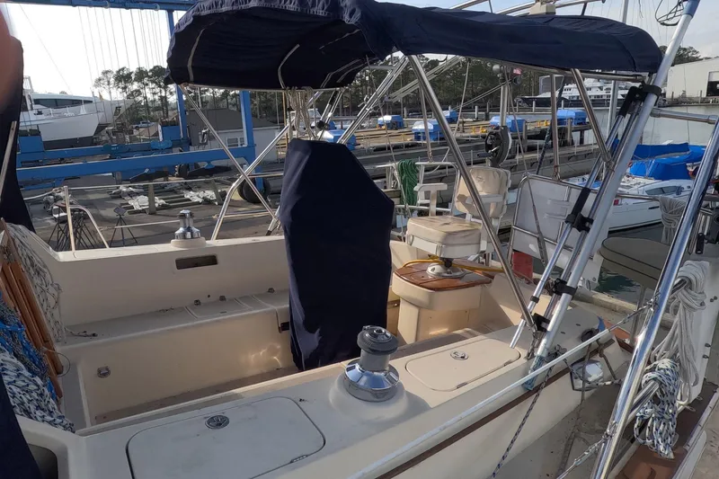 Slide: The Image of 2005 Island Packet 370 sailboat cockpit with covered seating and marina background. - 40