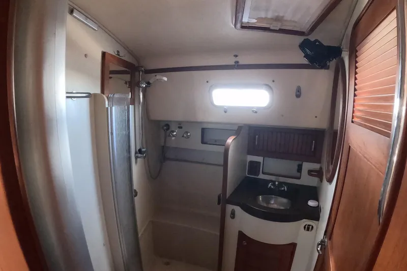 Slide: The Image of 2005 Island Packet 370 yacht bathroom with shower, sink, and wooden cabinetry. - 5
