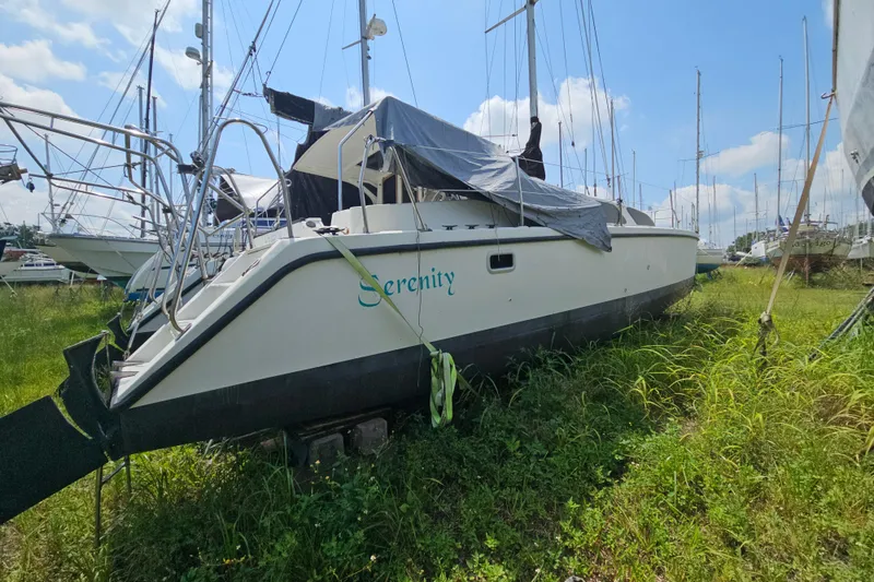 Slide: The Image of 2005 Gemini MC 105 sailboat named "Serenity" on grassy land, covered with tarp. - 12