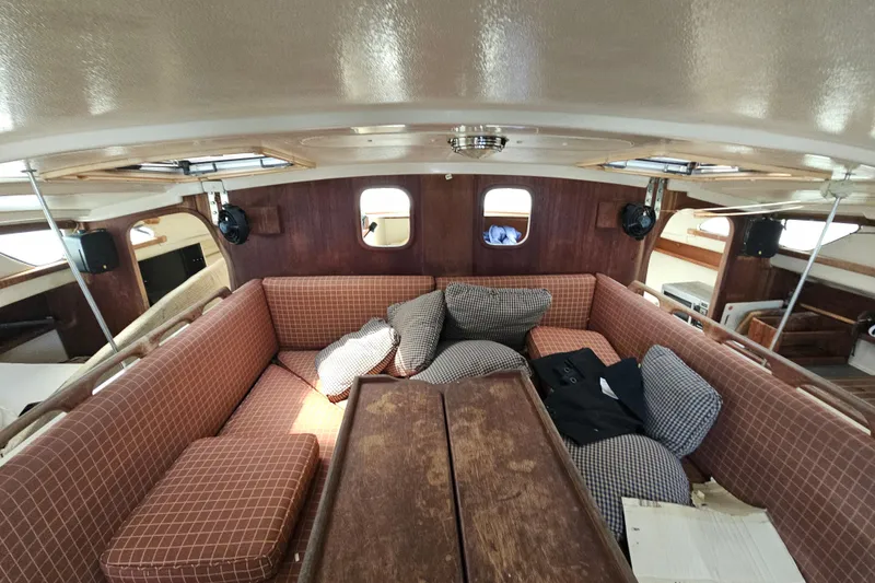 Slide: The Image of Interior of 2005 Gemini MC 105 sailboat with cushioned seating and wooden table. - 17