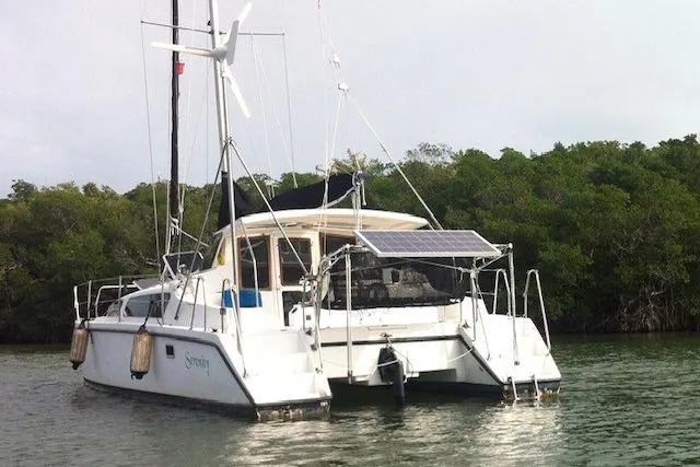 Slide: The Image of Catamaran Gemini MC 105, 2005 model, anchored near lush green shoreline. - 2