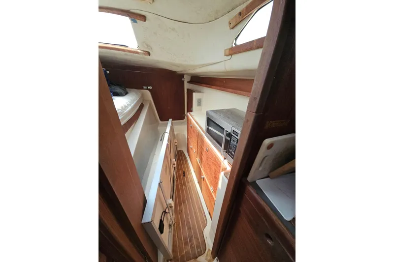 Slide: The Image of Interior of 2005 Gemini MC 105 sailboat with wood paneling and compact kitchen area. - 21