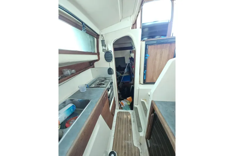 Slide: The Image of Interior of 2005 Gemini MC 105 boat, featuring compact kitchen and wooden accents. - 22