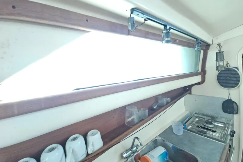 Slide: The Image of Interior of a 2005 Gemini MC 105 boat kitchen with wooden shelves and stainless steel sink. - 23
