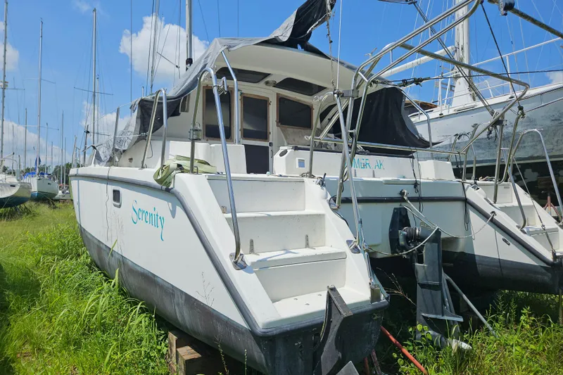 Slide: The Image of 2005 Gemini MC 105 catamaran named "Serenity" in a grassy boatyard under a clear sky. - 35
