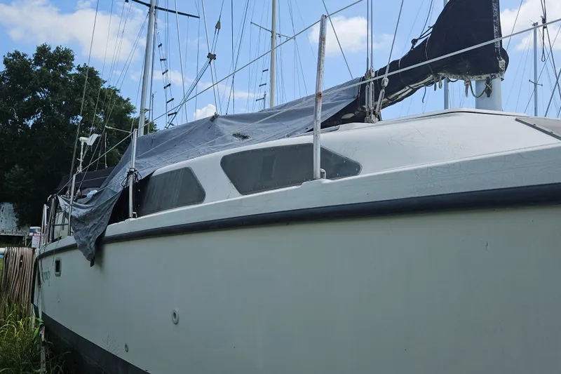 Slide: The Image of 2005 Gemini MC 105 sailboat with tarp cover, docked under blue sky. - 7