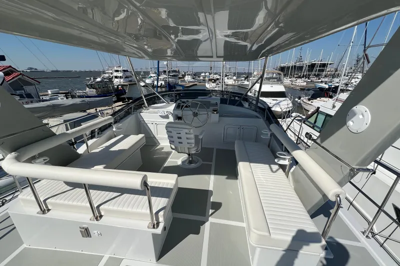 Slide: The Image of Helmsman Trawlers 43E Pilothouse 2025, spacious deck with seating, docked at marina. - 3