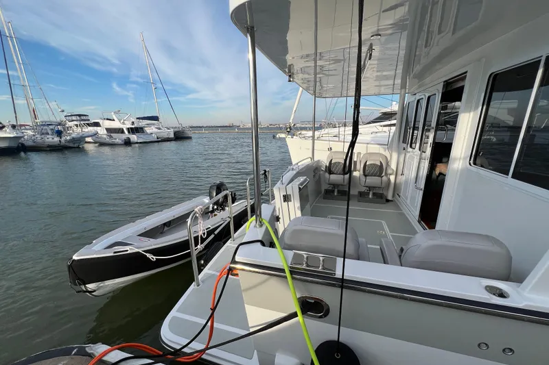 Slide: The Image of Helmsman Trawlers 43E Pilothouse 2025 docked, featuring spacious deck and nearby boats. - 5