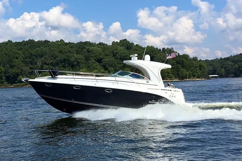 The Image of 2008 Rinker 400 Express Cruiser speeding on a lake with lush green shoreline. - 0