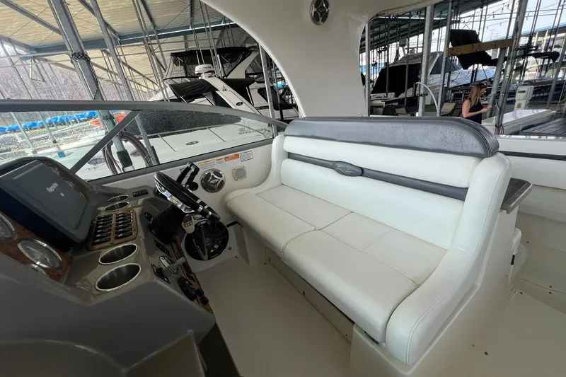 Slide: The Image of 2008 Rinker 400 Express Cruiser helm with white seating and control panel in marina. - 3