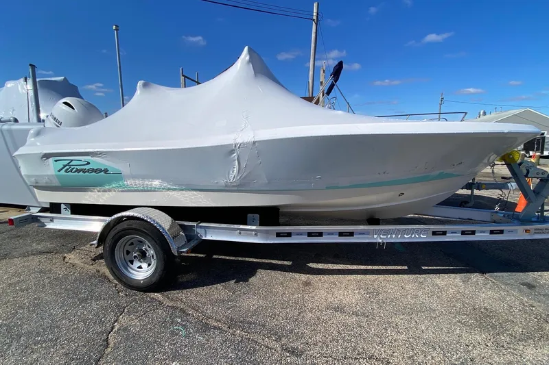 Slide: The Image of 2026 Pioneer 180 Sportfish boat covered on trailer under clear blue sky. - 4